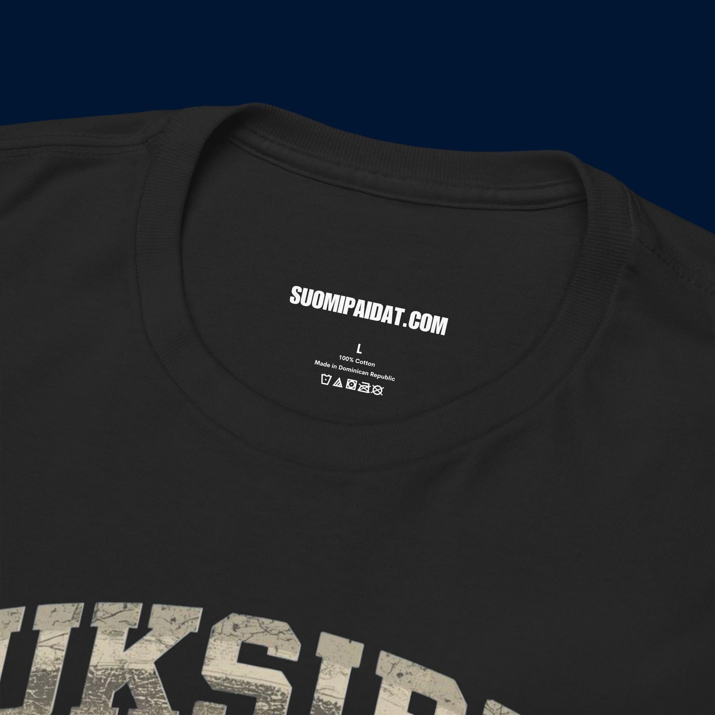 Suomipaidat.comin logolappu mustan Suksippa vittuun t-paidan sisäpuolella, 100% puuvillaa.